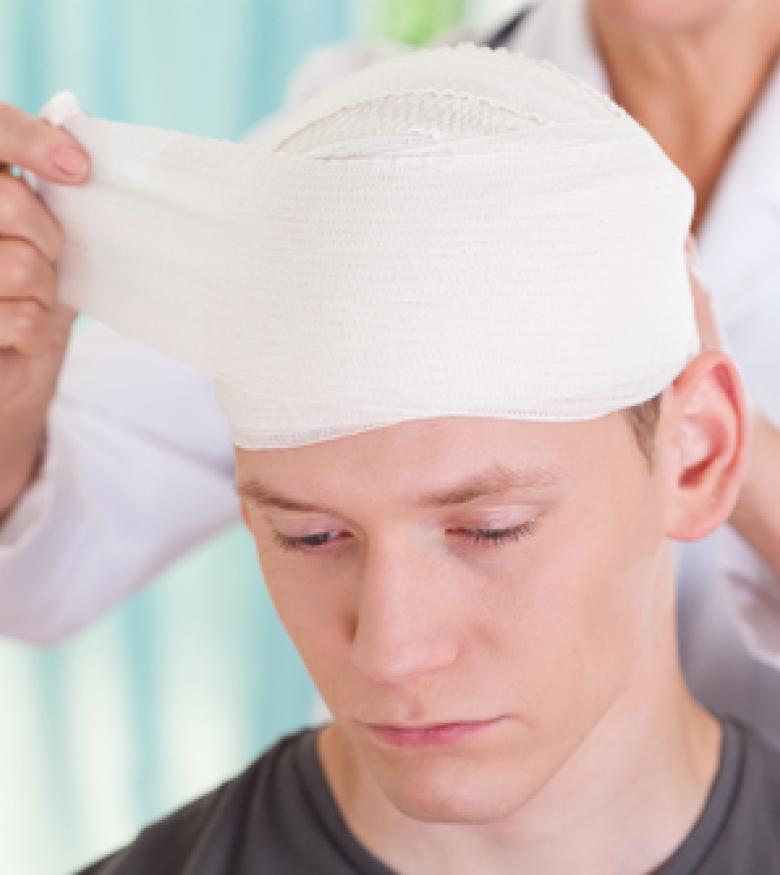 A doctor bandaging a young man's head injury, emphasizing the importance of seeking a Brain Injury Attorney in Gainesville for legal support.