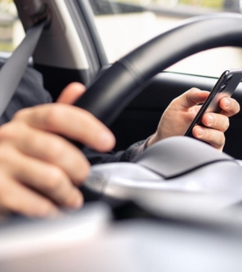 A driver using a phone while driving, highlighting the need for a Rideshare Accident Attorney in Gainesville to provide legal assistance.