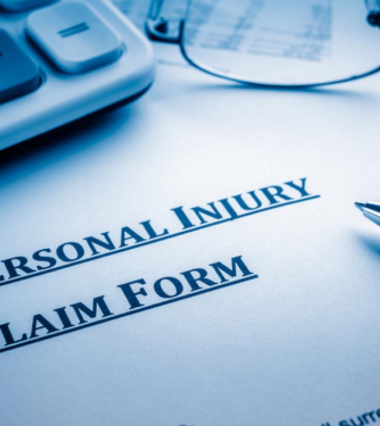 A close-up of a personal injury claim form, pen, and calculator, highlighting the need for an Injury Attorney in Daytona Beach for legal assistance.
