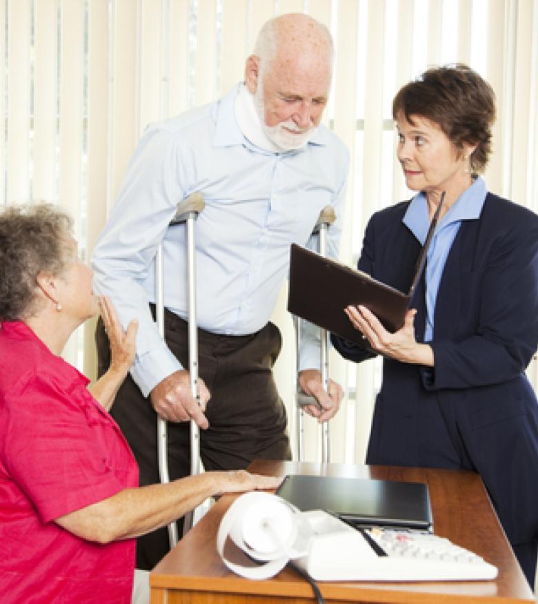 An elderly man on crutches consulting with a lawyer and a woman, emphasizing the need for an Injury Lawyer in Brunswick to provide legal assistance.