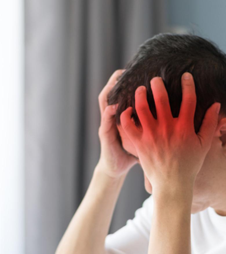 A person holding their head in pain with a red highlight, emphasizing the need for a Brain Injury Attorney in Covington to provide legal assistance.