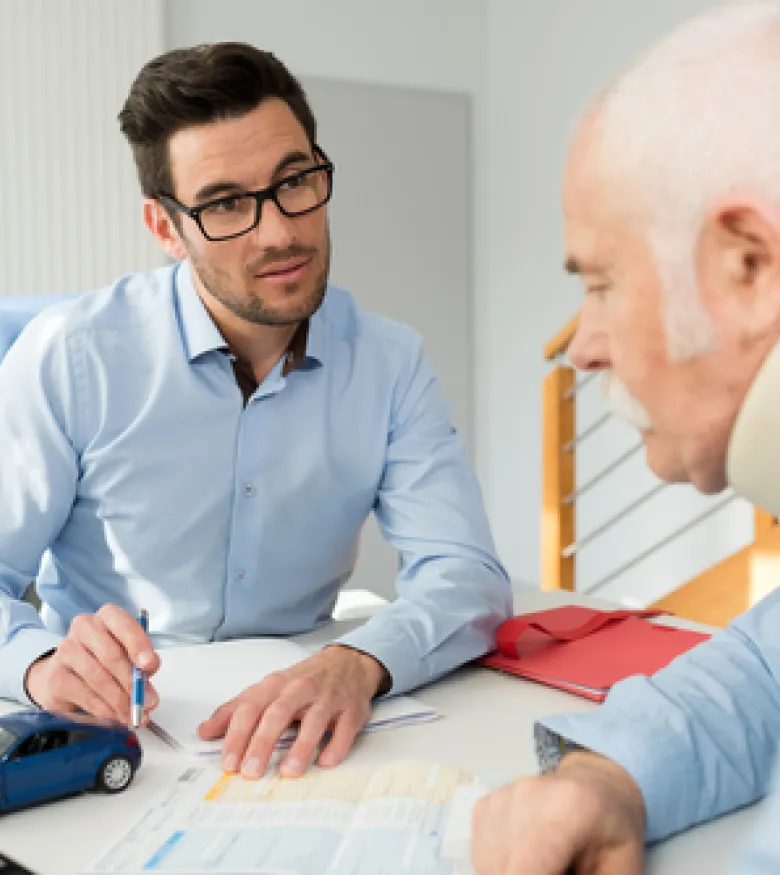 A lawyer consulting with an elderly man wearing a neck brace, emphasizing the need for an Injury Attorney in The Bronx to provide legal assistance.