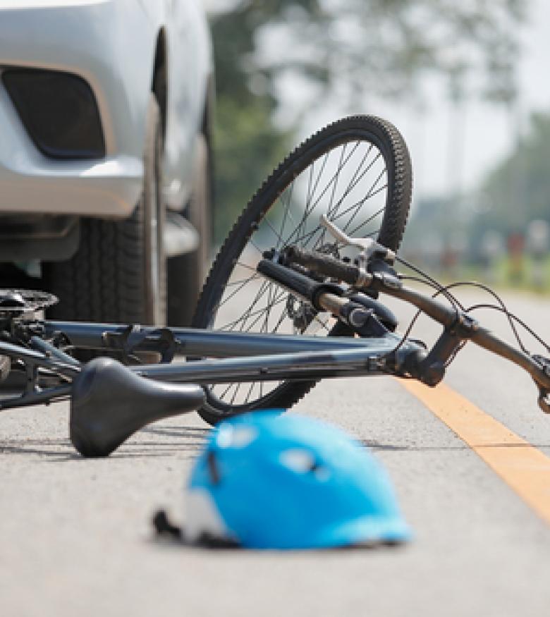 A bicycle and helmet lying on the road next to a car, highlighting the need for a Bicycle Accident Attorney in Bowling Green to provide legal assistance.