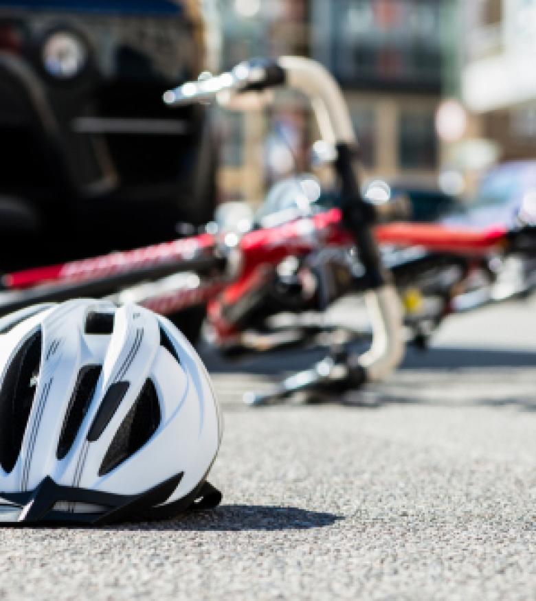 A bicycle and helmet on the ground near a car accident scene, highlighting the need for a Bicycle Accident Attorney in Gainesville for legal assistance.