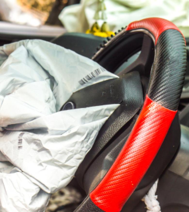  Deflated airbags in a car with a red and black steering wheel cover after an accident, depicting Airbag Injuries in Lakeland