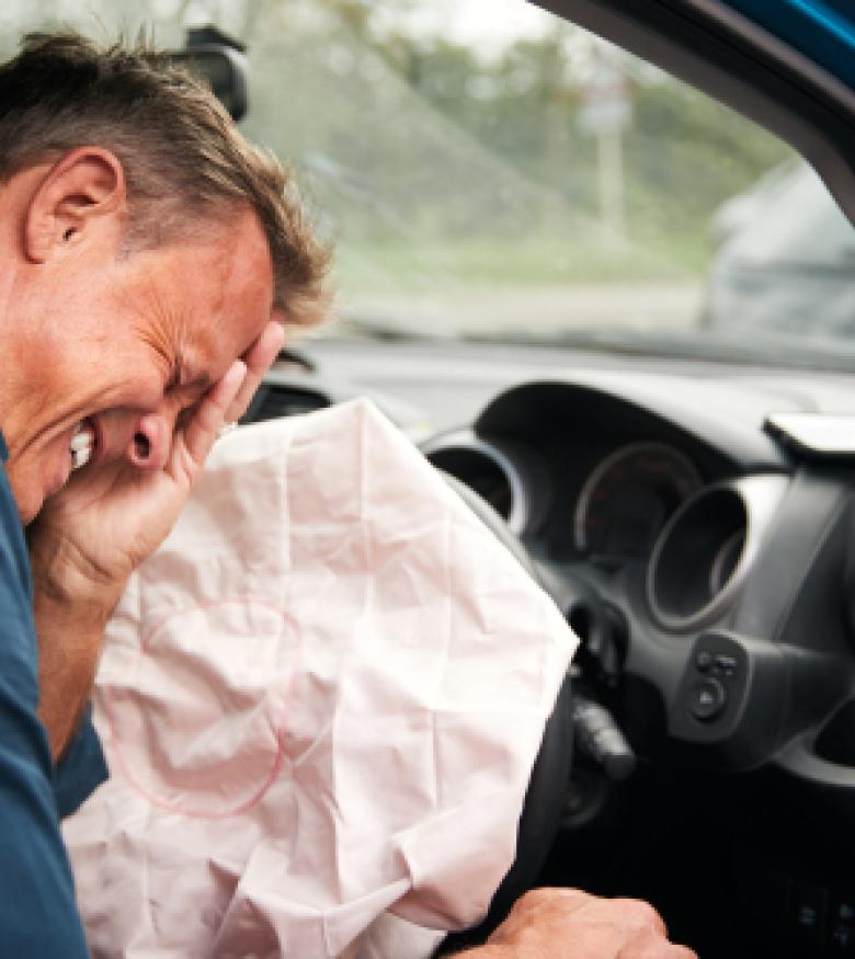 Man experiencing pain after an airbag deployment in a car, illustrating the need for an attorney specializing in airbag injuries in Daytona Beach.