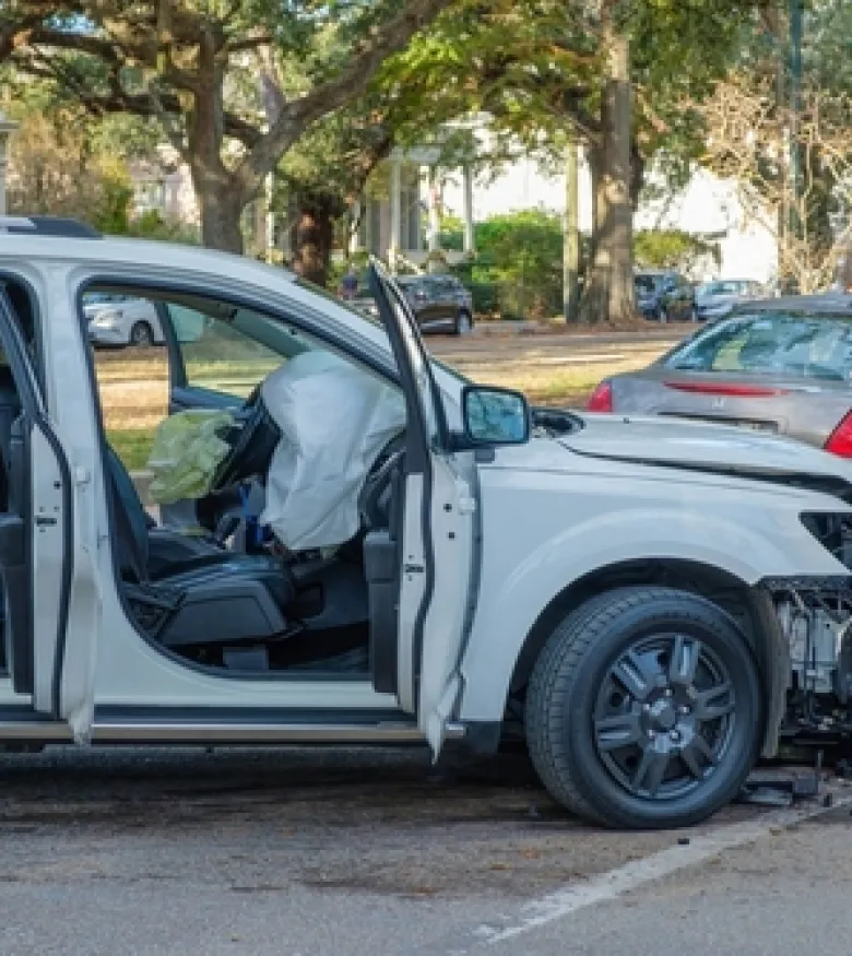 A white SUV with deployed airbags and front-end damage after a collision, illustrating Airbag Injuries in Palm Harbor.