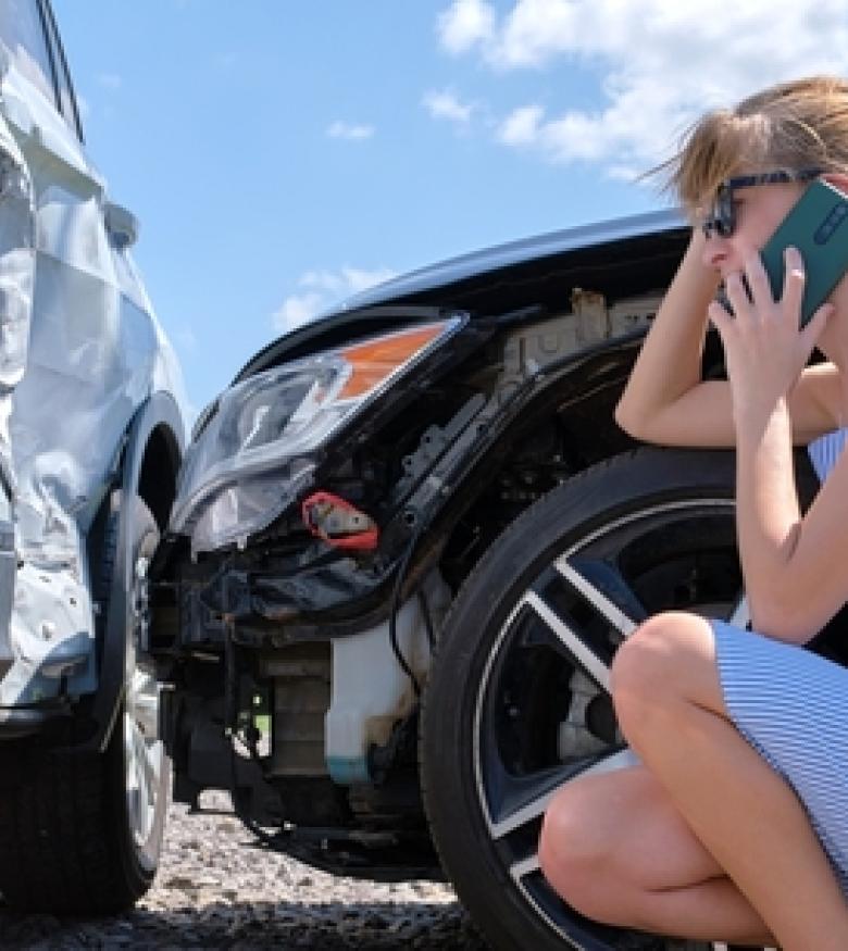 A woman on her phone next to two damaged cars after an accident, highlighting the need for a Car Wreck Attorney in Bradenton.