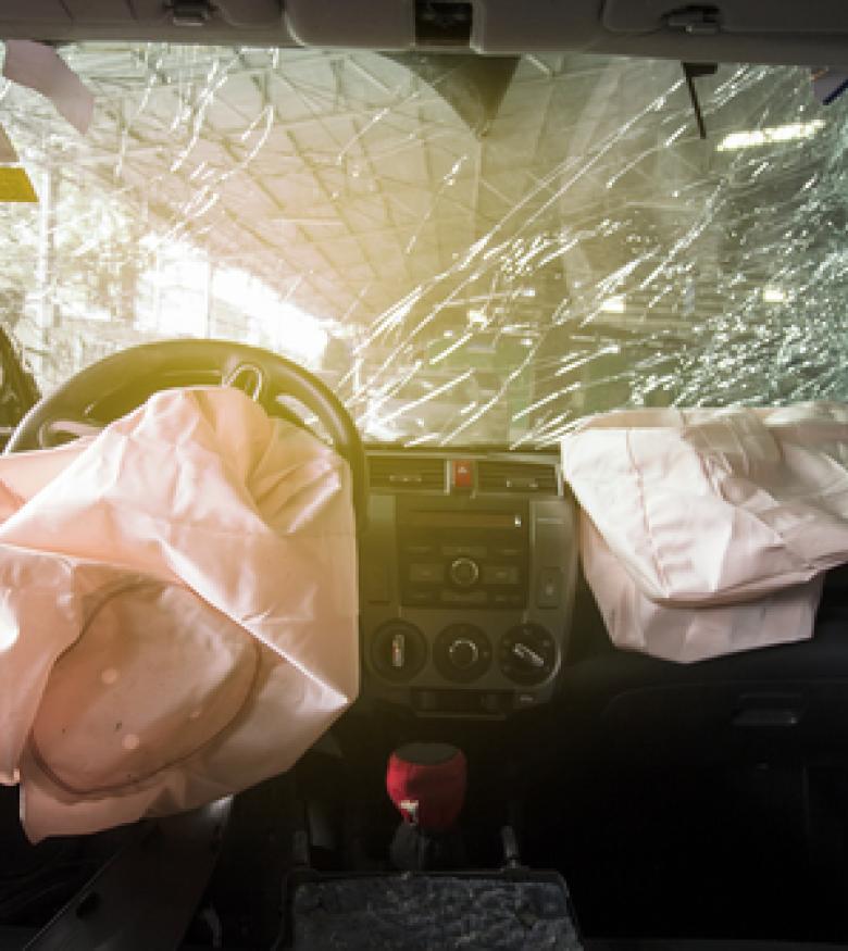 A car's interior with deployed airbags and a shattered windshield, highlighting the severity of Airbag Injuries in Manhattan.