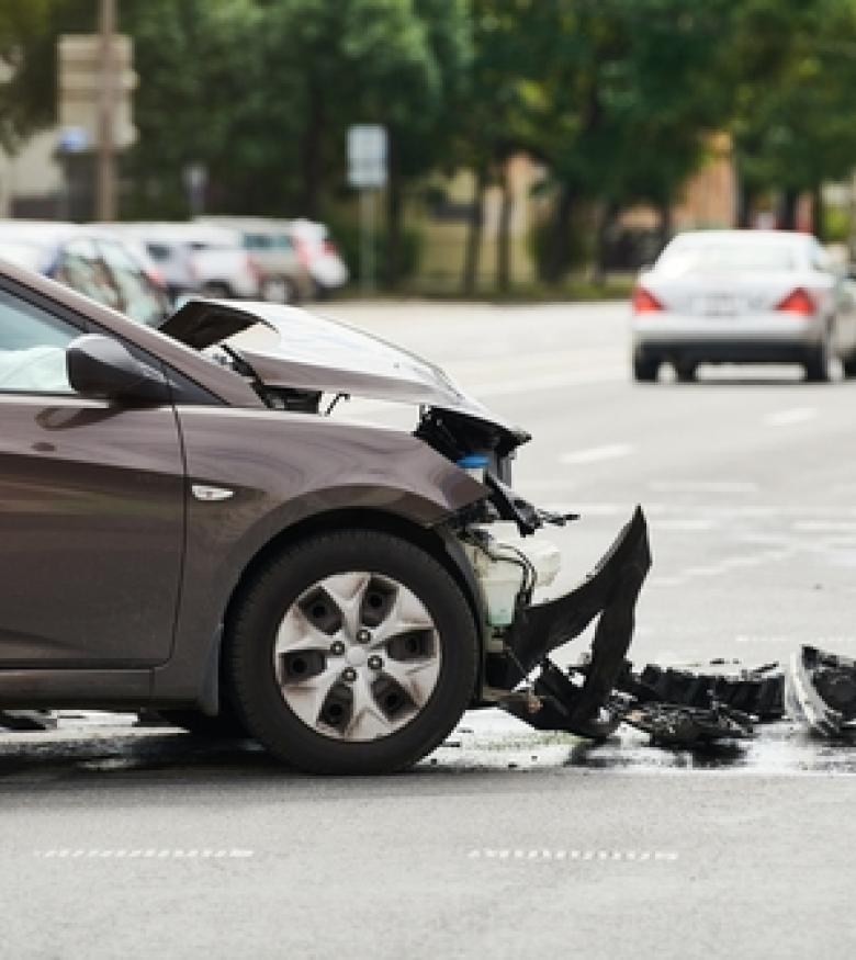 A car with significant front-end damage at an intersection, representing the need for a Car Wreck Attorney in Macon.