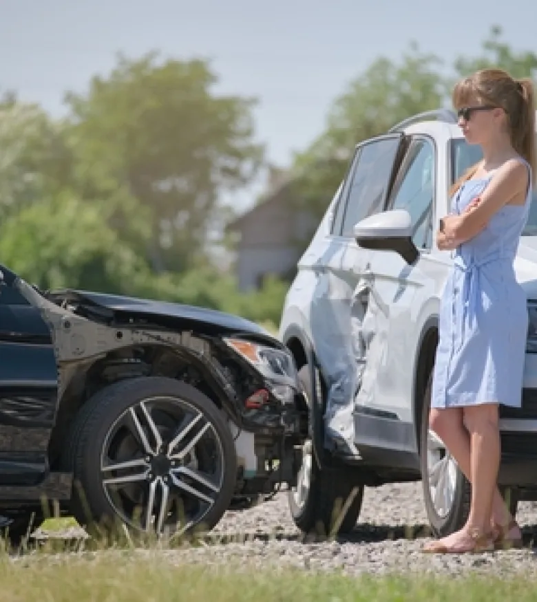 Woman standing near two damaged cars after a collision, highlighting the need for a car wreck lawyer in Marietta.