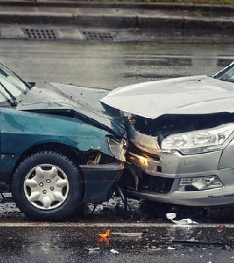 Head-on collision between two cars on a rainy street, highlighting the need for a Car Wreck Lawyer in The Villages