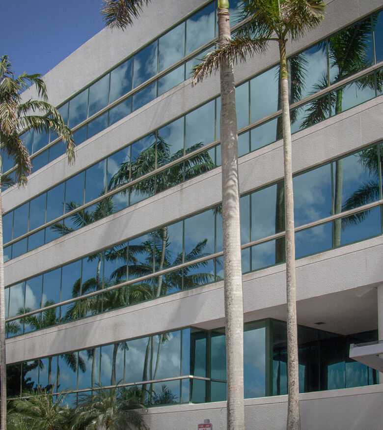 Modern glass building in Fort Lauderdale surrounded by palm trees, a strategic location for personal injury lawyers.