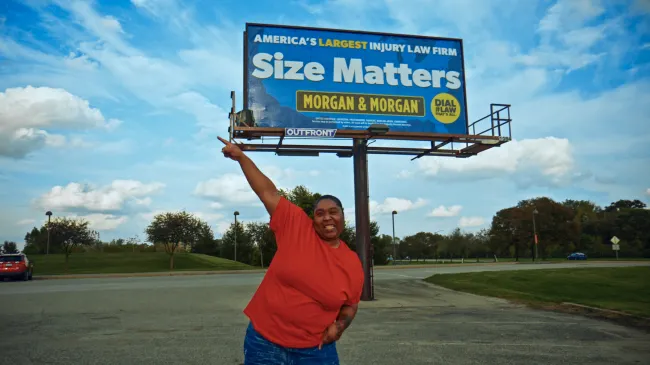 Raynetta standing near a Morgan & Morgan billboard that says size matters