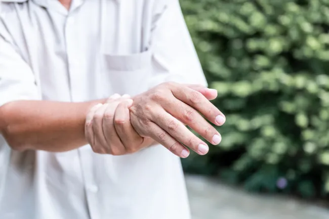 Elderly person holding their wrist in pain