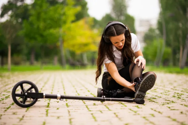 Woman on ground suffering a Scooter Ankle Injury