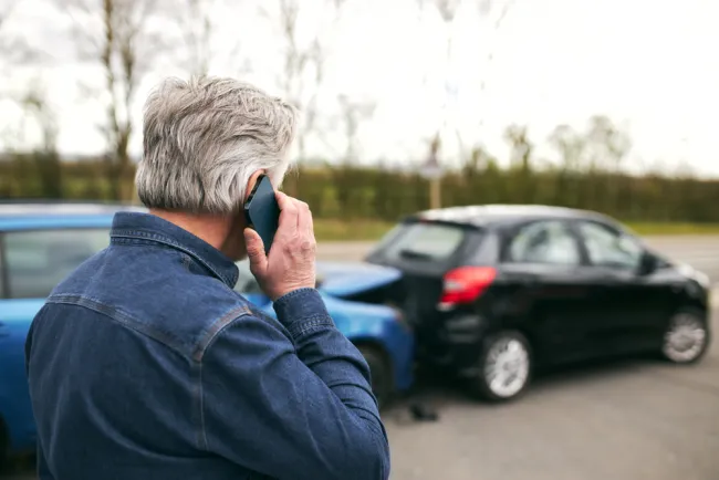 Man on the phone in front of two cars after an accident