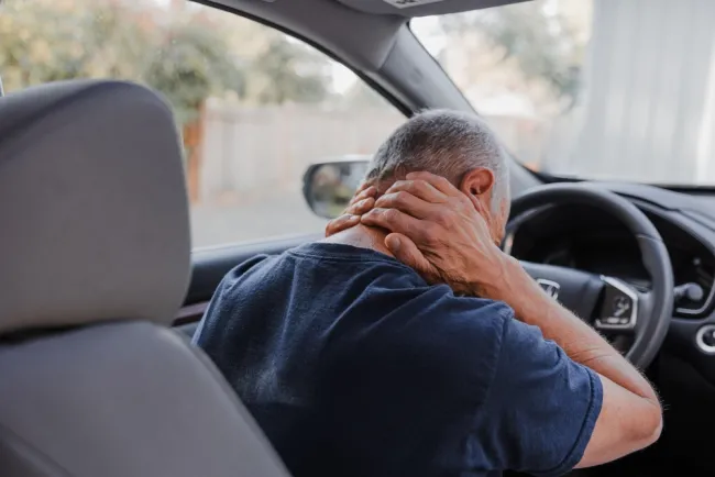 Man holding back in pain sitting in a car