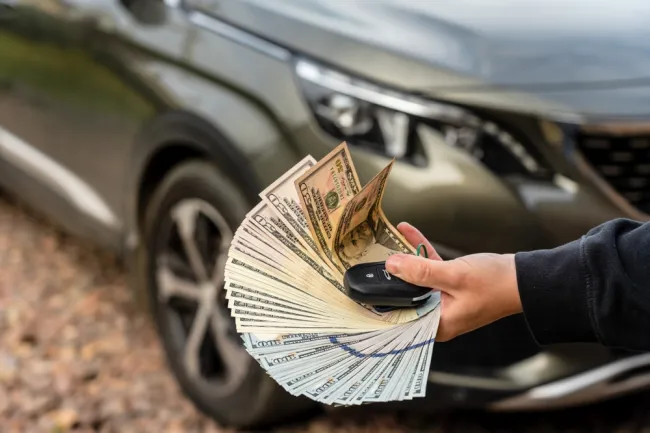 Person fanning money in front of a car with keys