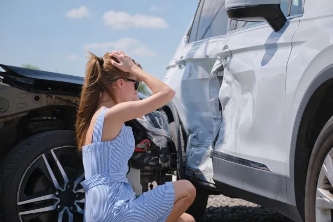 Woman in distress looking at her car after an accident