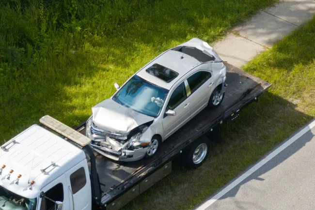 Damaged car on the back of a semi truck bed