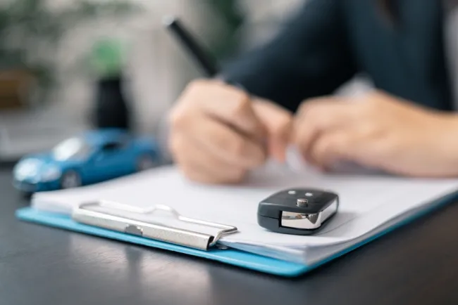 Someone writing on a clipboard with car keys on it