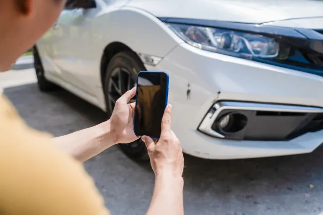 Man taking a picture of a damaged car