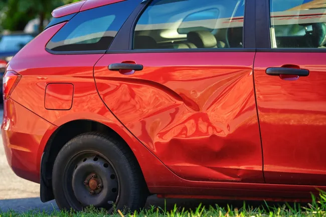 Red car with a dent on the side