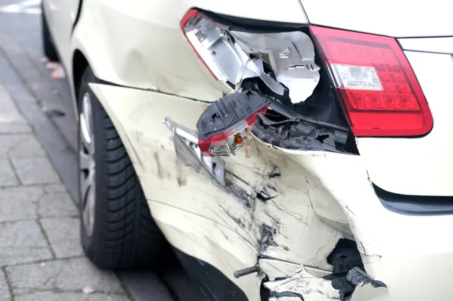 White car with a severely damaged tail light