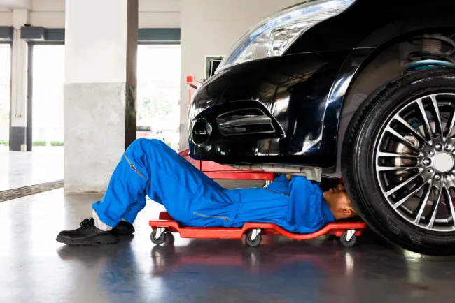 Mechanic wearing a blue jumpsuit working under a car